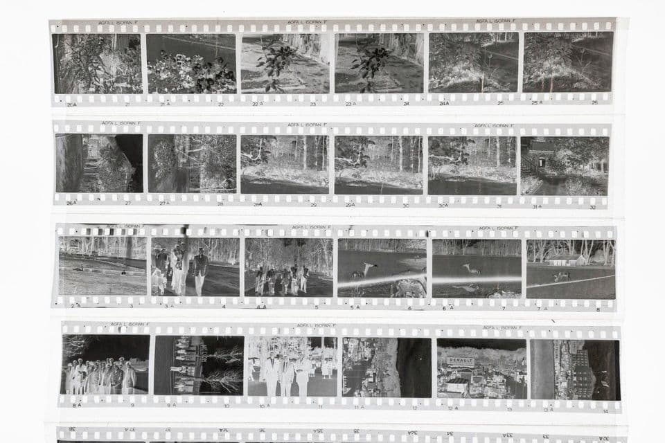 A black and white photographic contact sheet, four strips of 35 mm negatives laid out on a white surface, every frame numbered along the perforated edge and the film marked AGFA ISOPAN F