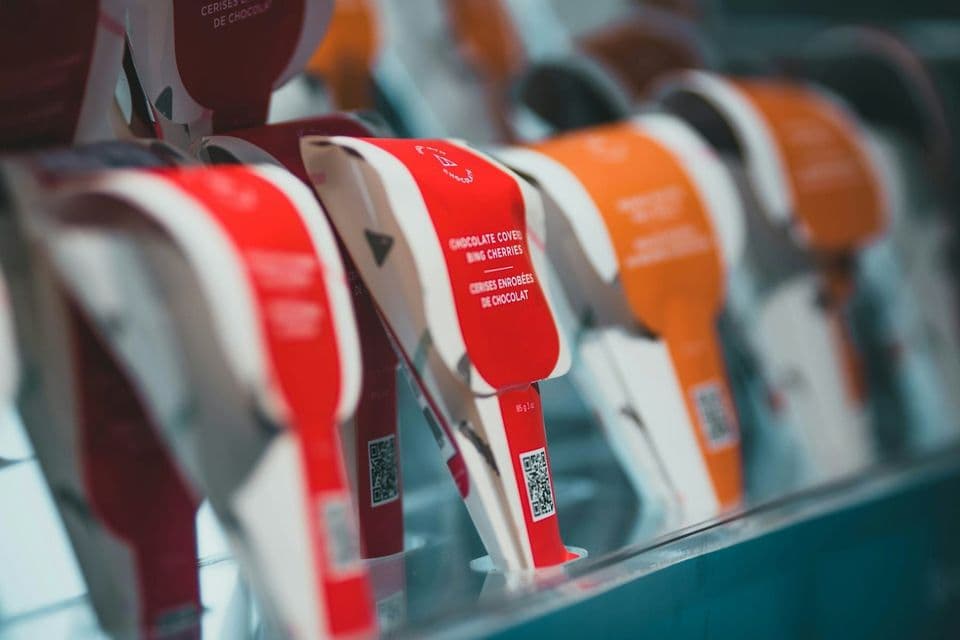 A row of brightly coloured packets standing upright in a display rack, one in sharp focus and the rest falling out of focus along the line